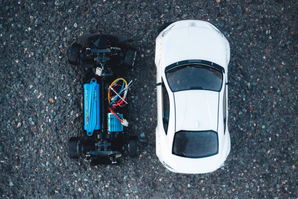 Aerial view of two electric toy cars on asphalt surface, showcasing their intricate designs.